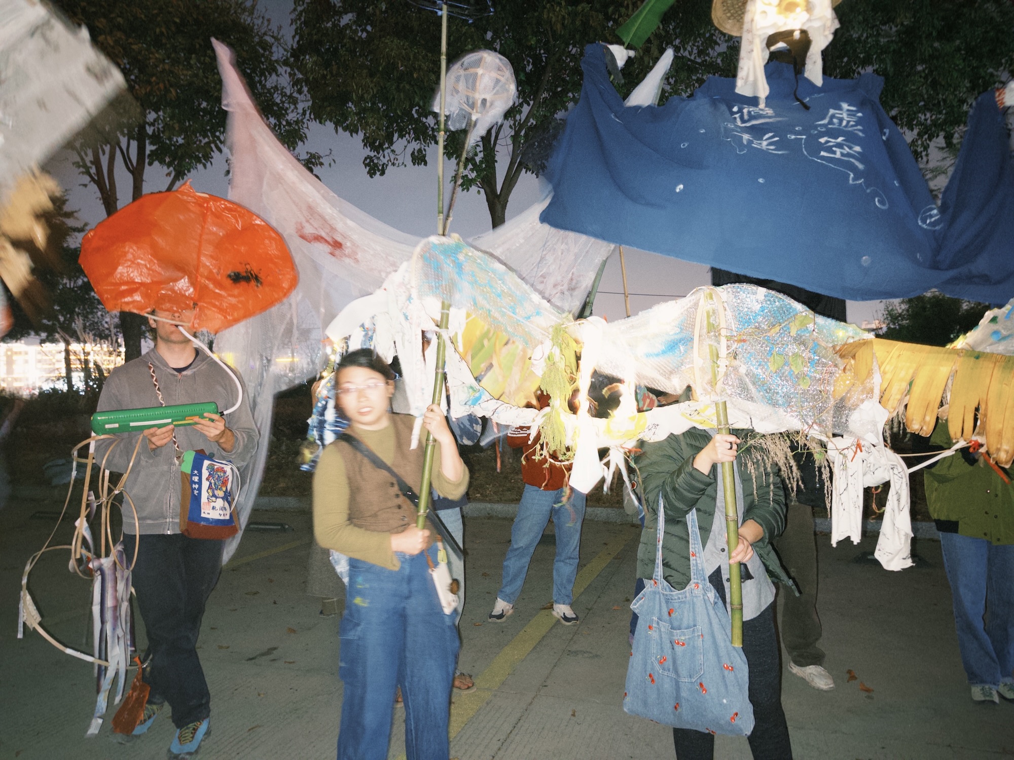 Group of young artists standing on parking lot carrying various colourful puppets