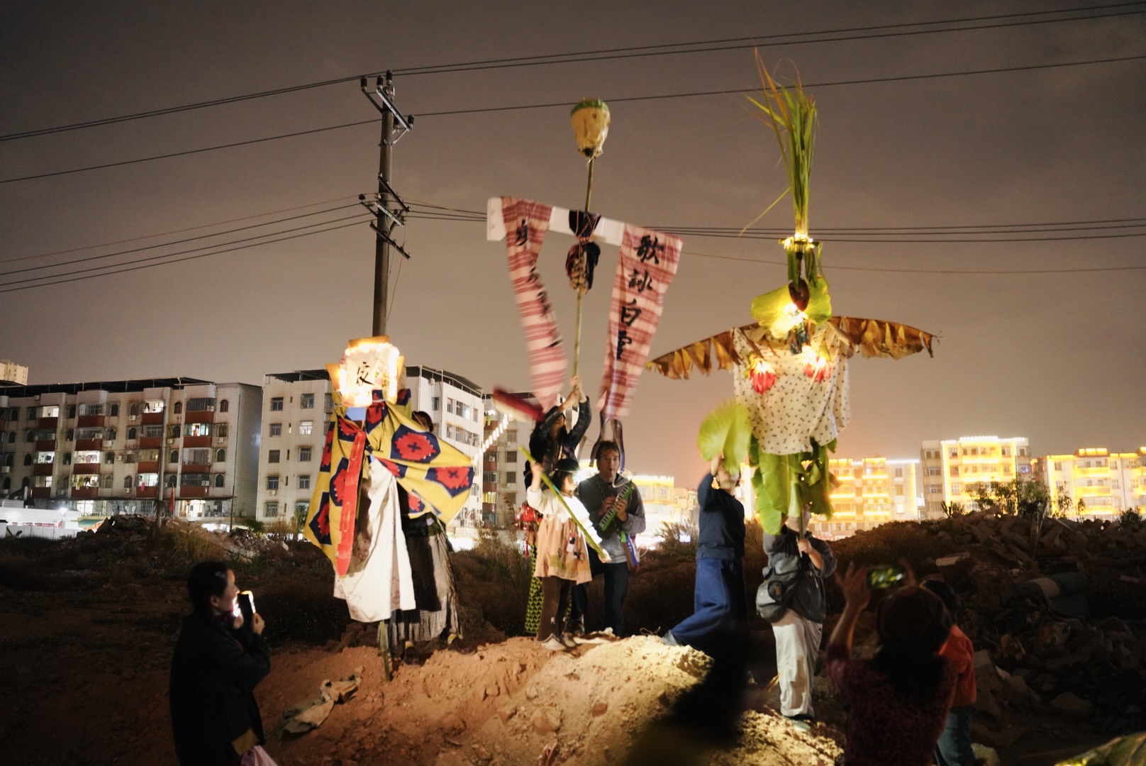 Group of young artists standing on top of dirthill presenting various colourful puppets